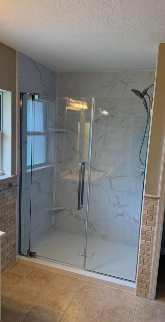 Walk-in shower with marble-look walls and glass panel